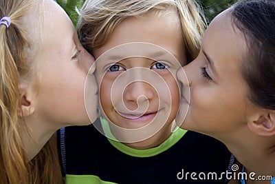 Cute blonde boy kissed by two girls Stock Photo