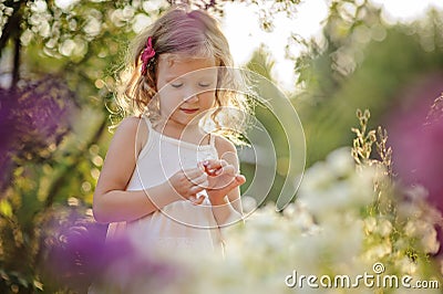 Cute blonde child girl in blooming summer garden Stock Photo