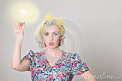 Cute blonde retro girl holding glowing light bulb - humorous con Stock Photo