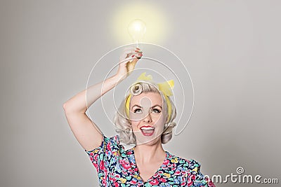 Cute blonde retro girl holding glowing light bulb - humorous con Stock Photo