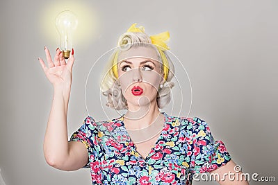 Cute blonde retro girl holding glowing light bulb - humorous con Stock Photo