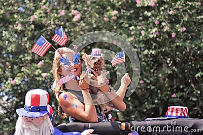Cute blonde, Yorkshire terrier and puppet are covered head to toe with American Flags Editorial Stock Photo