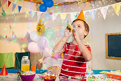 Cute boy blowing party horn during birthday party Stock Photo