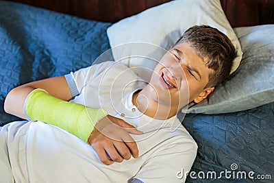 Cute boy with broken hand hearts. Close up young handsome Teenage with elbow plaster at home Stock Photo