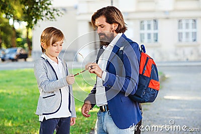 Cute boy and father walking to school. Bearded man with son wearing fashion suits outdoors. Father takes child to school Stock Photo
