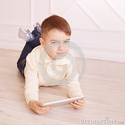 Cute boy. Computer tablet. play game, chat. Training. light interior Stock Photo