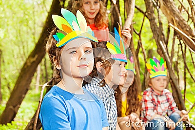 Cute boy in Injun`s headdress playing with friends Stock Photo