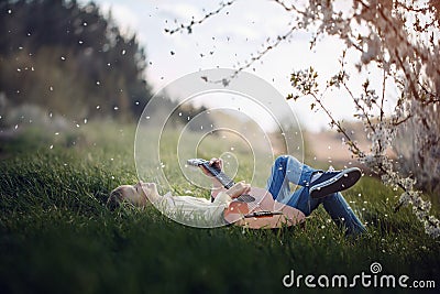 Cute boy lies on the grass with a guitar on sunset Stock Photo