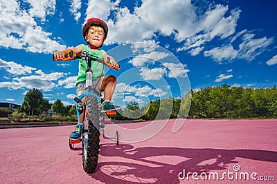 Cute boy on little bicycle in helmet ride at park over blue sky Stock Photo