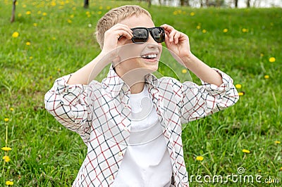 Cute boy with no tooth put on colorblind sunglasses and looks up Stock Photo