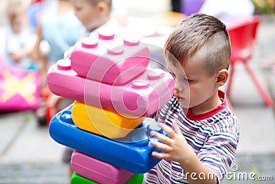 Cute boy playing with buiding toy colorful blocks. Kid with happy face playing with plastic bricks. Plastic Large Toy Stock Photo