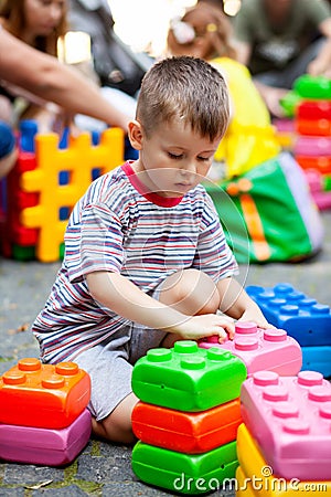 Cute boy playing with buiding toy colorful blocks. Kid with happy face playing with plastic bricks. Plastic Large Toy Stock Photo