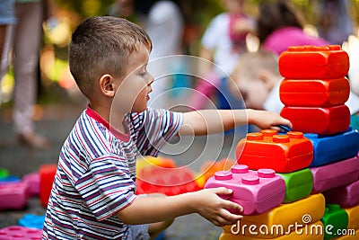 Cute boy playing with buiding toy colorful blocks. Kid with happy face playing with plastic bricks. Plastic Large Toy Stock Photo