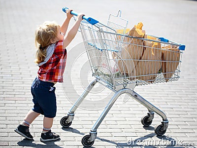 Cute boy pushing shopping trolley Stock Photo