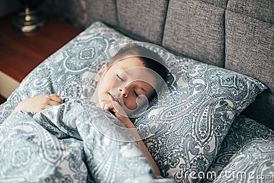 Cute boy sleeping in bed. Child 6-7 years old smiling, having a good dreams Stock Photo