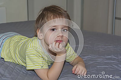 A cute boy in a striped T-shirt. Portrait of a blond boy in a natural setting. The face expresses natural emotions Stock Photo