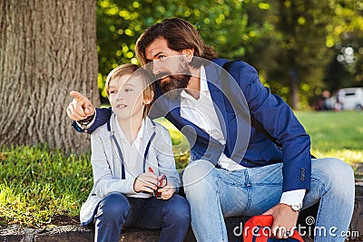 Cute boy talking with dad on a walk after school. Bearded man and his son outside Stock Photo