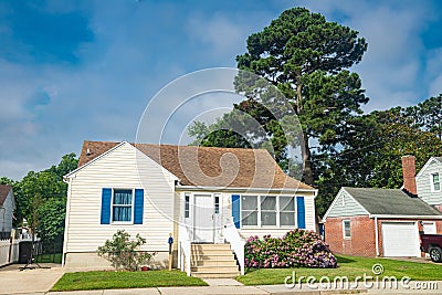 Cute brightly painted white shingled cottage with blue shutters. coastal town on sunny day Editorial Stock Photo