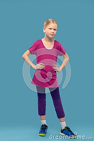 Cute calm girl in sportswear on blue background Stock Photo
