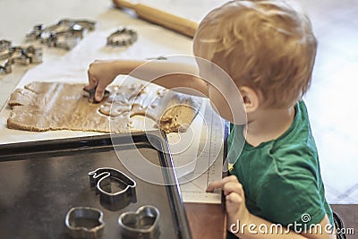 Cute caucasian baby boy helps in kitchen, making coockies. Casual lifestyle in home interior, pretty child alone. Stock Photo