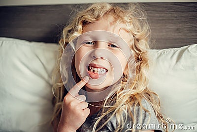 Cute Caucasian blonde girl showing her missing tooth in mouth. Proud child kid showing lost tooth and expecting a tooth fairy Stock Photo