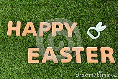 Cute ceramic bunny ears and text HAPPY EASTER made of wooden letters on green grass Stock Photo