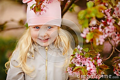 A cute charming blonde girl with lush hair on a pink sakura Stock Photo
