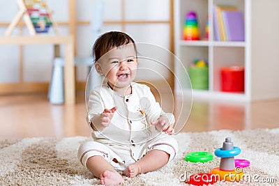 Cute cheerful baby playing with colorful toy at home Stock Photo