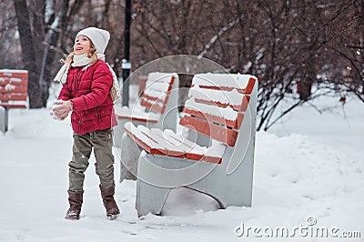 Cute cheerful child girl making snowball in winter snowy park Stock Photo