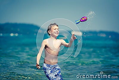 Cute cheerful child in swimware playing in sea with toy Stock Photo