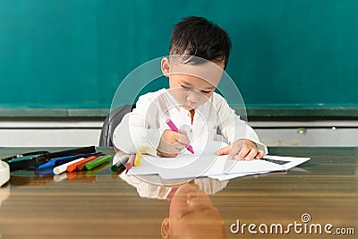 Cute child Asian boy doing homework. Clever kid drawing at desk. Schoolboy. Elementary school student drawing at workplace. Kid Stock Photo