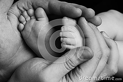 Cute child baby babe little foot in the father hands. Classical closeup shot about family values and parents child children love. Stock Photo