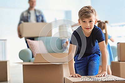 Cute child with box with his family packing belongings at home. Moving into new house Stock Photo