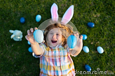 Cute child bunny wear rabbit ears in garden, Happy Easter day. Bunny boy, funny outdoor portrait. Hunting eggs and Stock Photo