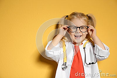 Cute child in doctor coat with stethoscope on color background. Stock Photo