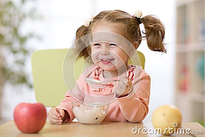 Child eating healthy food with the left hand at home Stock Photo