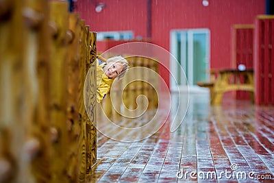 Cute child, enjoying little fishing village with rorbuer cabins on a heavy rainy day Stock Photo