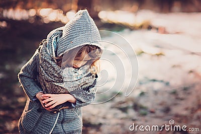 Cute child girl in grey knitted coat plays on the walk in winter forest Stock Photo
