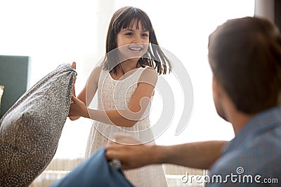 Cute child girl having funny pillow fight with dad Stock Photo