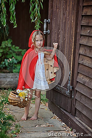 Cute child girl plays little red riding hood in summer garden Stock Photo