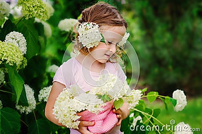 Cute child with hydrangea flowers bouquet in summer garden near flowering bush Stock Photo