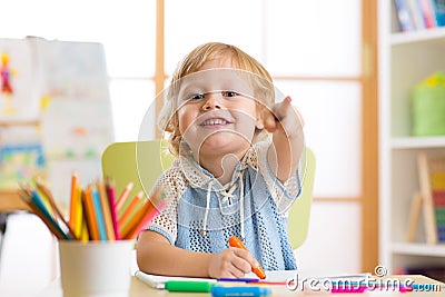 Cute child little boy drawing with felt-tip pen in kindergarten classroom Stock Photo