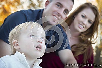 Cute Child Looks Up to Sky as Young Parents Smile Stock Photo