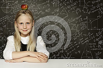 Cute child student girl with red apple on head. Blackboard background with science formulas. Learning science concept Stock Photo