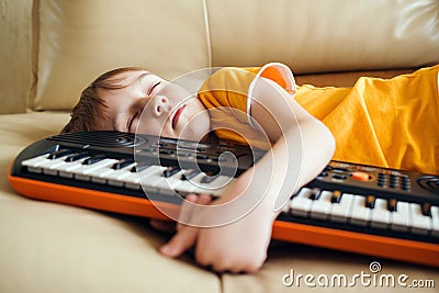 Cute child tired of learning to play the synthesizer. Kids hobbies and leisure. Future profession Stock Photo