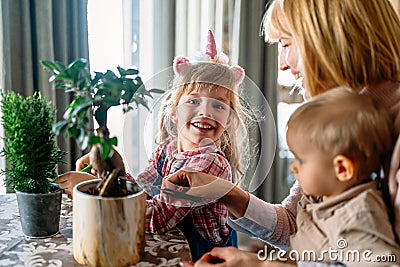 Cute children helping her mother to care for plants. Mom and her kids engaging in gardening at home. Stock Photo