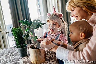 Cute children helping her mother to care for plants. Mom and her kids engaging in gardening at home. Stock Photo