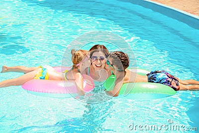 Cute children kissing their mother in swimming pool Stock Photo