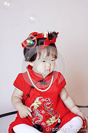 Cute Chinese little baby in red cheongsam play soap bubbles Stock Photo