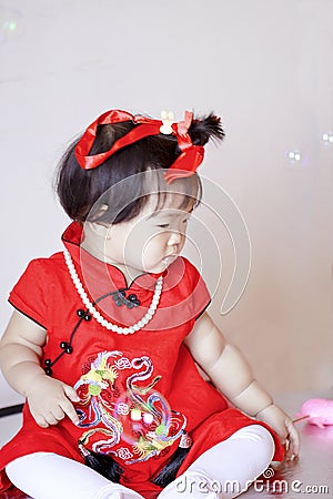 Cute Chinese little baby in red cheongsam play soap bubbles Stock Photo